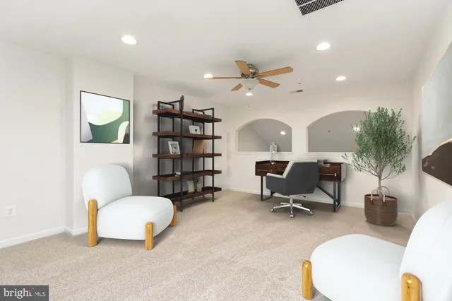 an empty room with ceiling fan and kitchen view