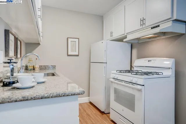 a kitchen with granite countertop white cabinets and white appliances
