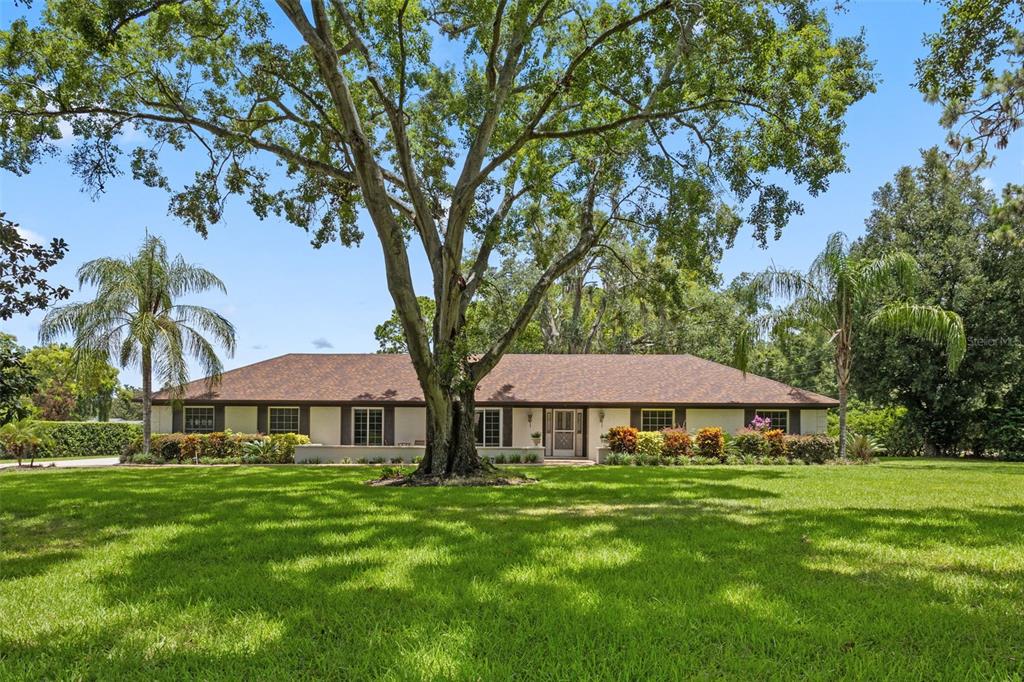 a front view of a house with garden and trees