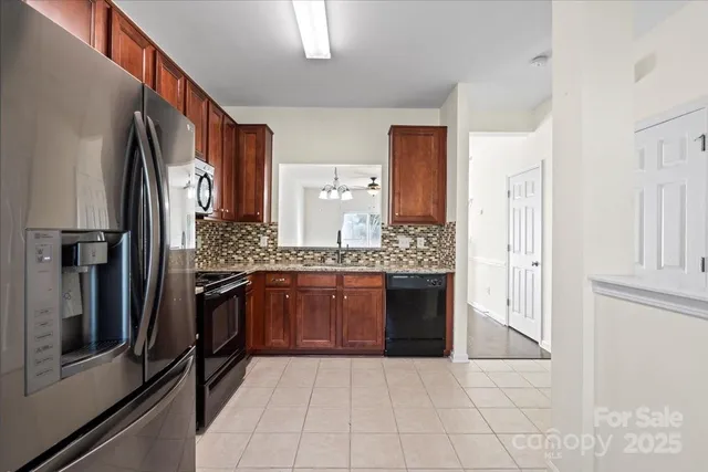 a kitchen with stainless steel appliances granite countertop wooden cabinets a stove a sink and a refrigerator