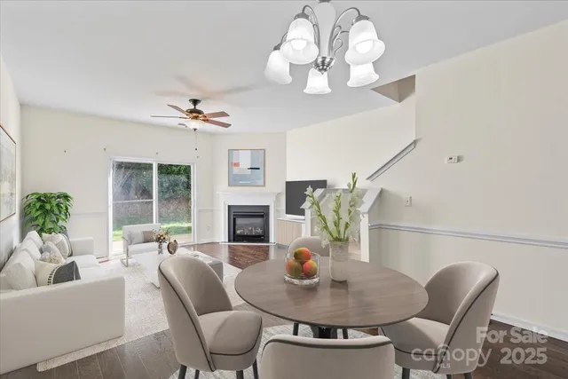 a view of a livingroom with wooden floor a ceiling fan and windows
