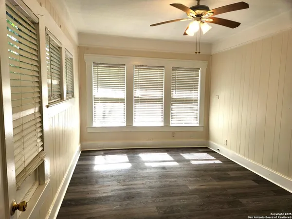 a view of an empty room with wooden floor and a window