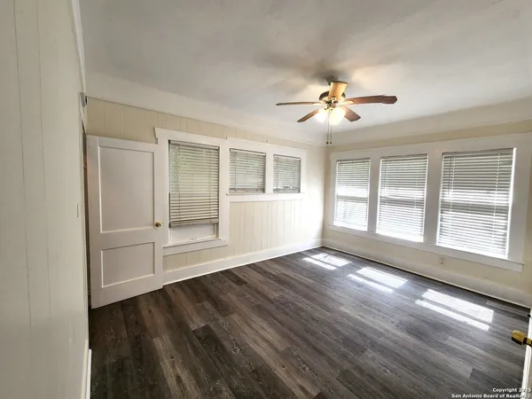 a view of an empty room with a window and wooden floor