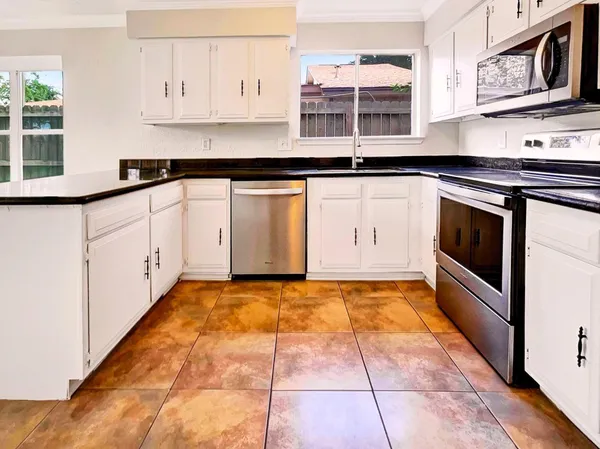 a kitchen with granite countertop a sink a stove and cabinets