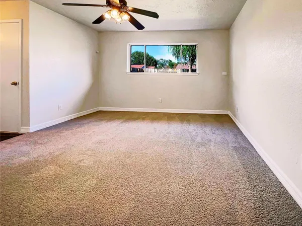 an empty room with a ceiling fan and carpet