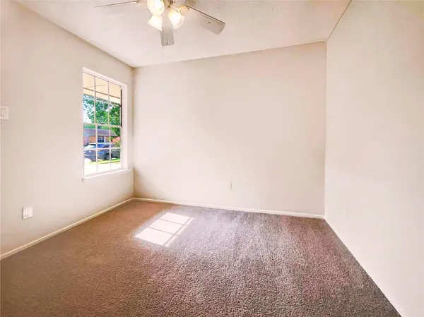 an empty room with windows and fan