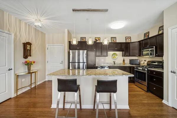 a large kitchen with kitchen island granite countertop a stove a sink a dining table and chairs