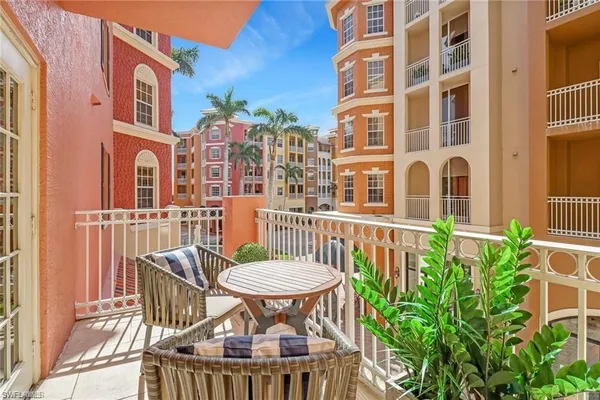 a view of a brick building from a chairs and table in the balcony