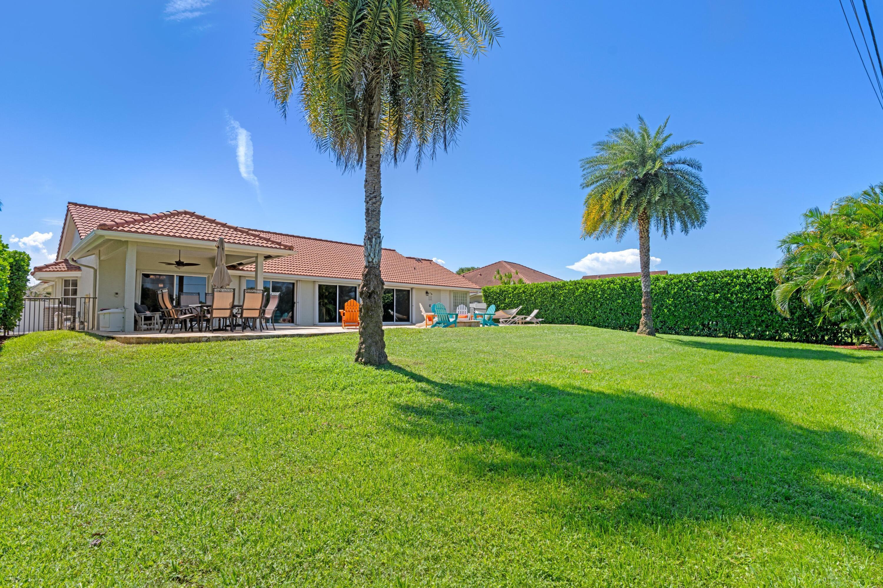 7598 Fairway Trail Boca Raton, FL 33487 - Photo 24 of 50 a view of a house with a big yard and palm trees