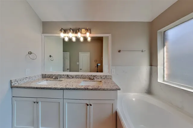 a bathroom with a granite countertop sink a large mirror and a bathtub