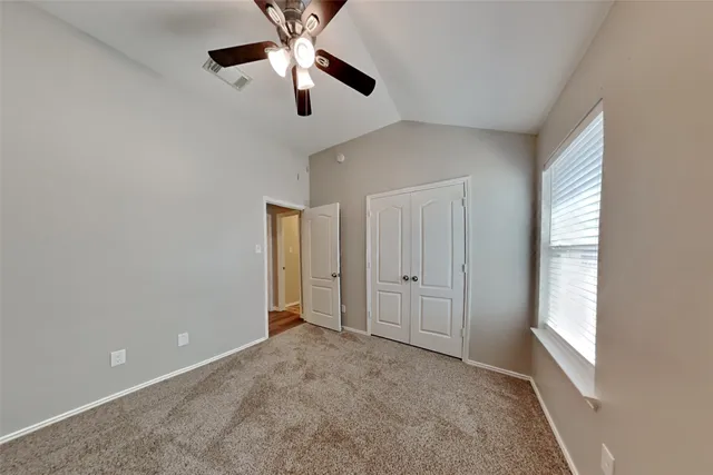 an empty room with windows and fan