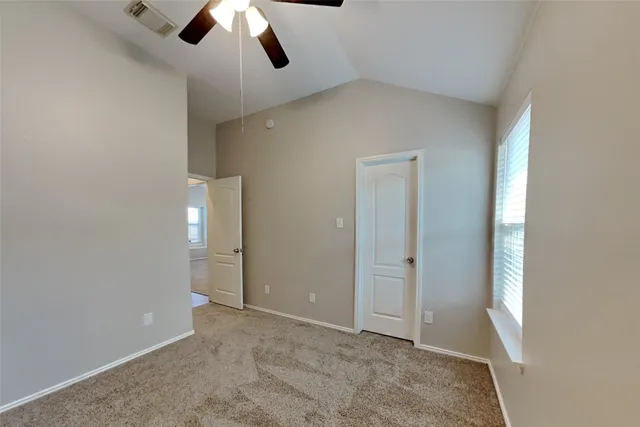 an empty room with ceiling fan and window