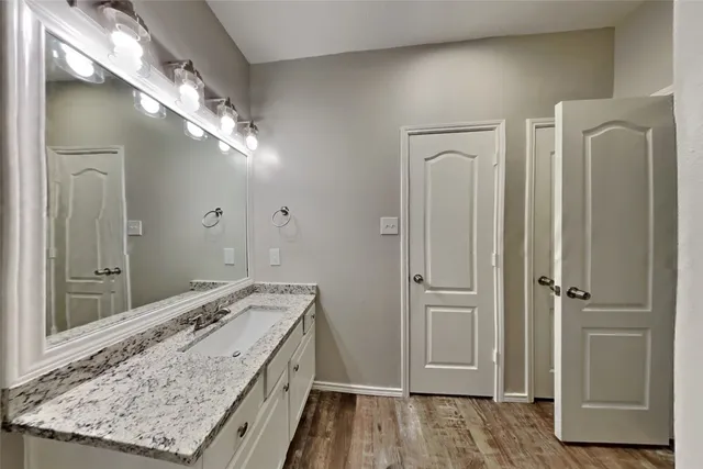 a bathroom with a granite countertop sink a mirror and shower