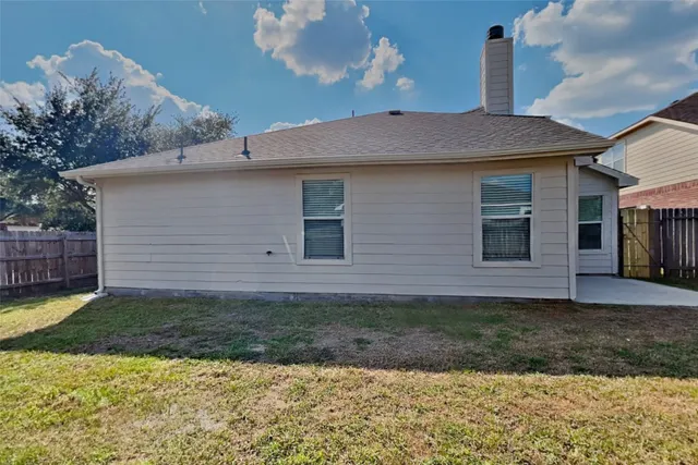 a brick house with a yard plants and large tree