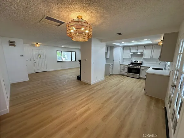 an open kitchen view with wooden floor and stainless steel appliances