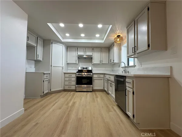 a kitchen with kitchen island granite countertop wooden floors stainless steel appliances a sink and a counter top