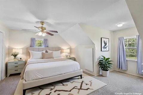 a bedroom with a bed chandelier painting on the wall and a large window