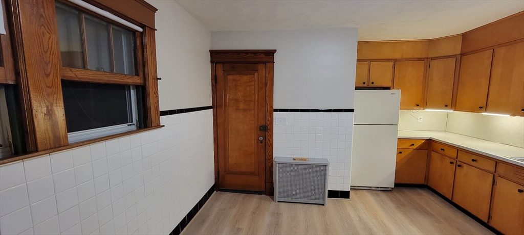 74 Melha Avenue Springfield, MA 01104 - Photo 6 of 16 a kitchen with a refrigerator a stove top oven a wooden floor and cabinets
