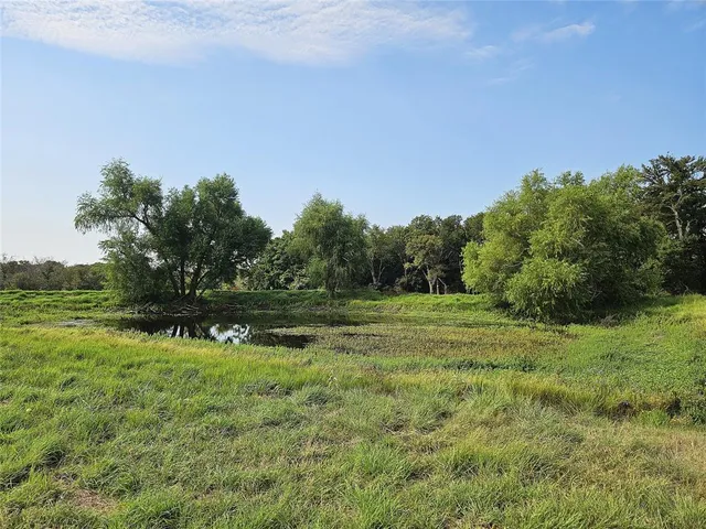 a view of a green field with wooden fence