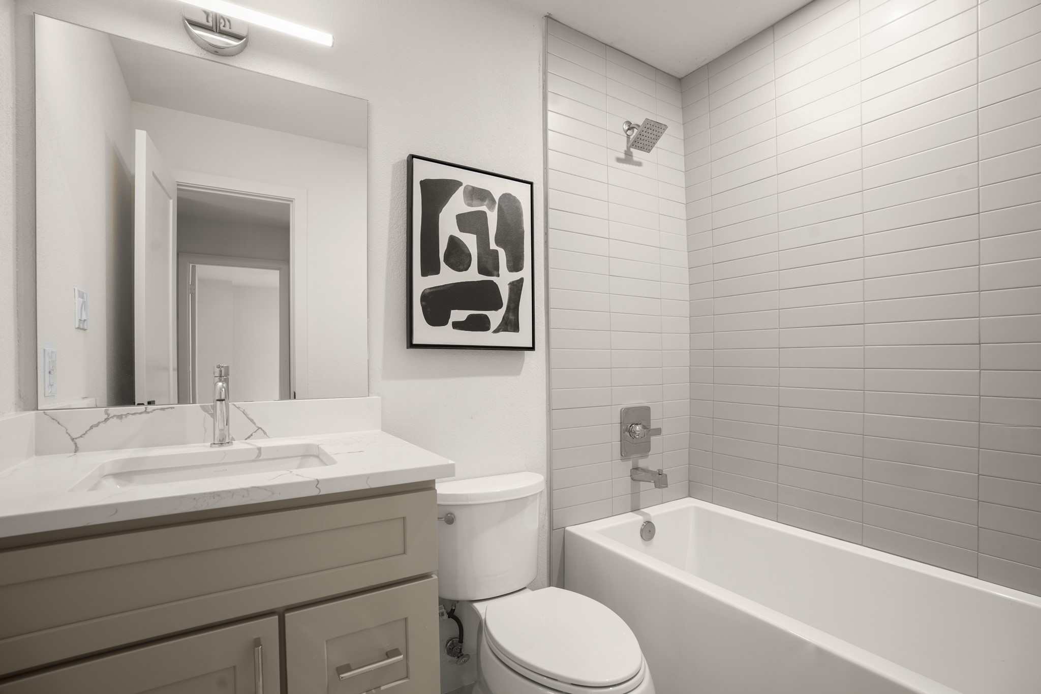7826 Wheel Rim Circle Austin, TX 78749 - Photo 22 of 38 A modern bathroom highlights a tiled shower surround, integrated tub, and quartz-topped vanity.