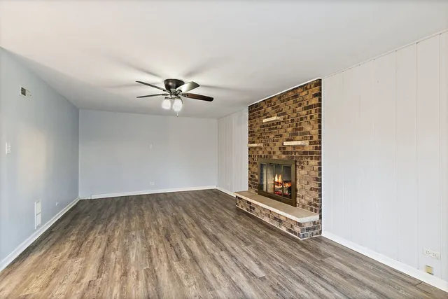 a view of a livingroom with wooden floor a ceiling fan and a window