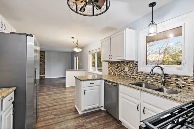 a kitchen with stainless steel appliances granite countertop a sink a stove and a refrigerator