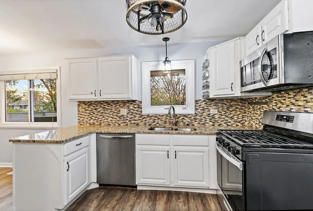 a kitchen with white cabinets appliances and a window