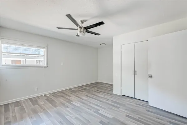 an empty room with wooden floor fan and windows