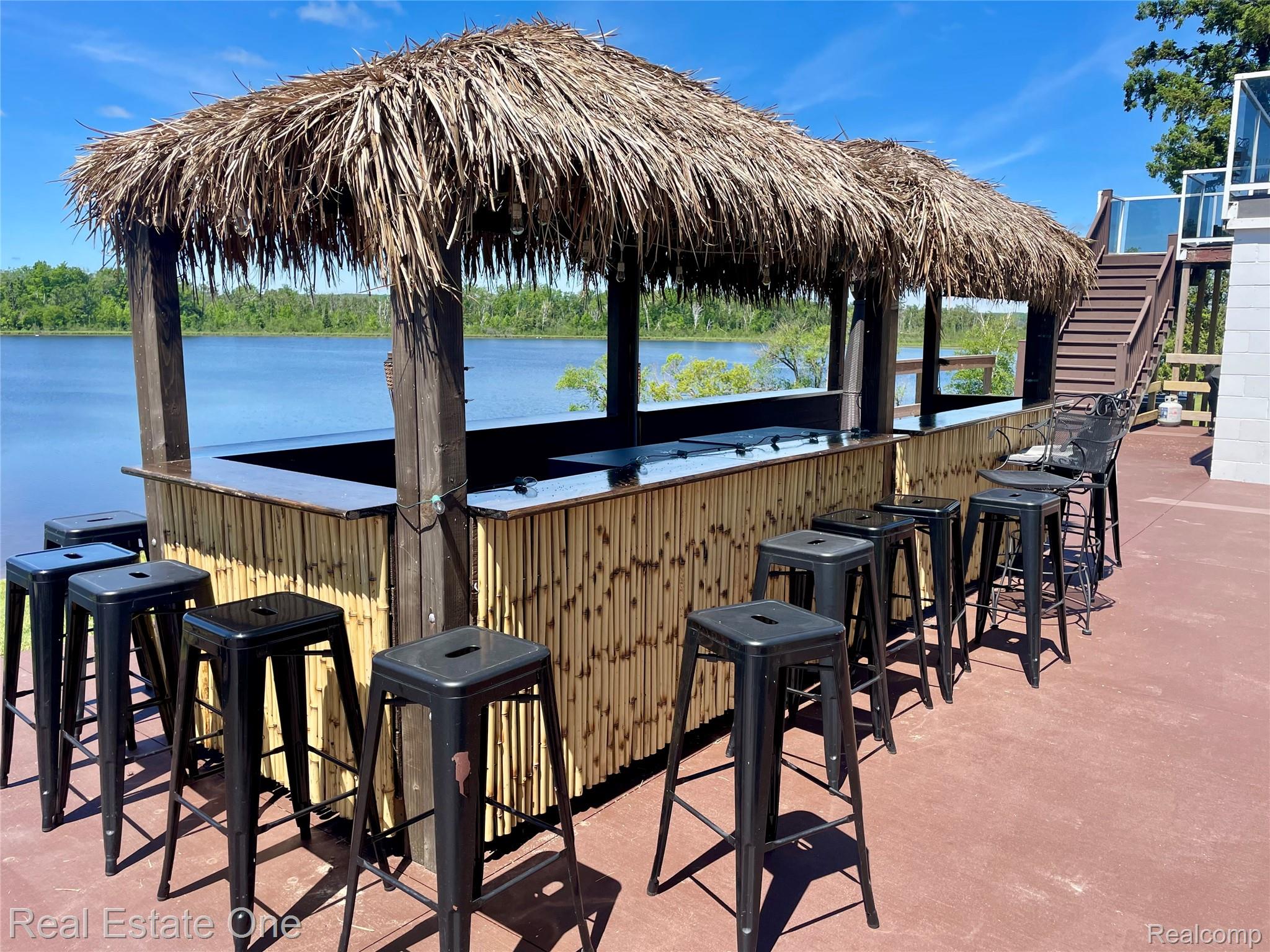 4160 Hawk Road Lincoln, MI 48742 - Photo 47 of 48 Waterfront bar featuring a thatched roof, wood posts, bamboo paneling, and a dark countertop