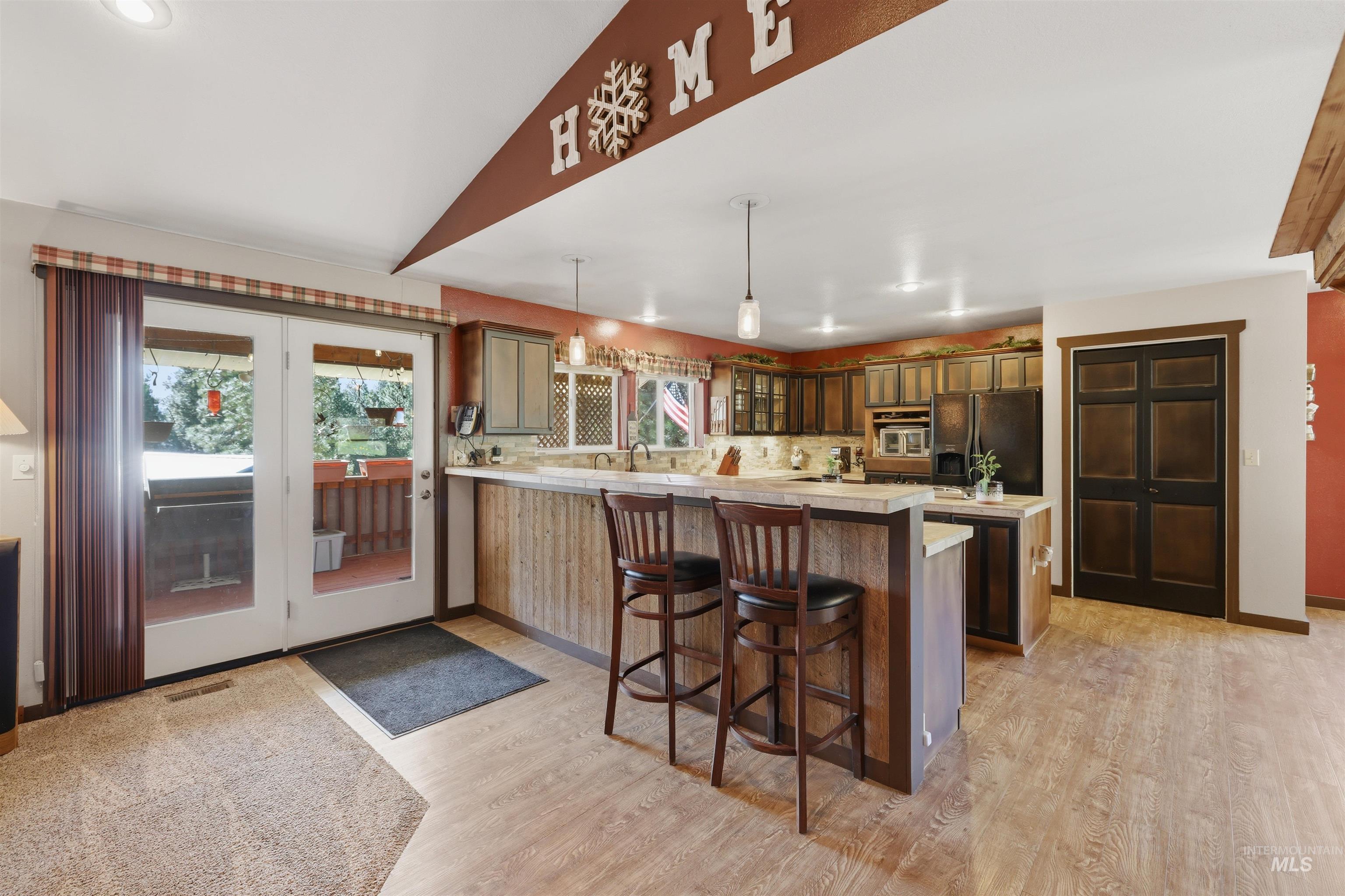 95 Johnson Creek Road Boise, ID 83716 - Photo 19 of 49 Kitchen with a kitchen breakfast bar, a peninsula, lofted ceiling, glass fronted cabinets, and black fridge