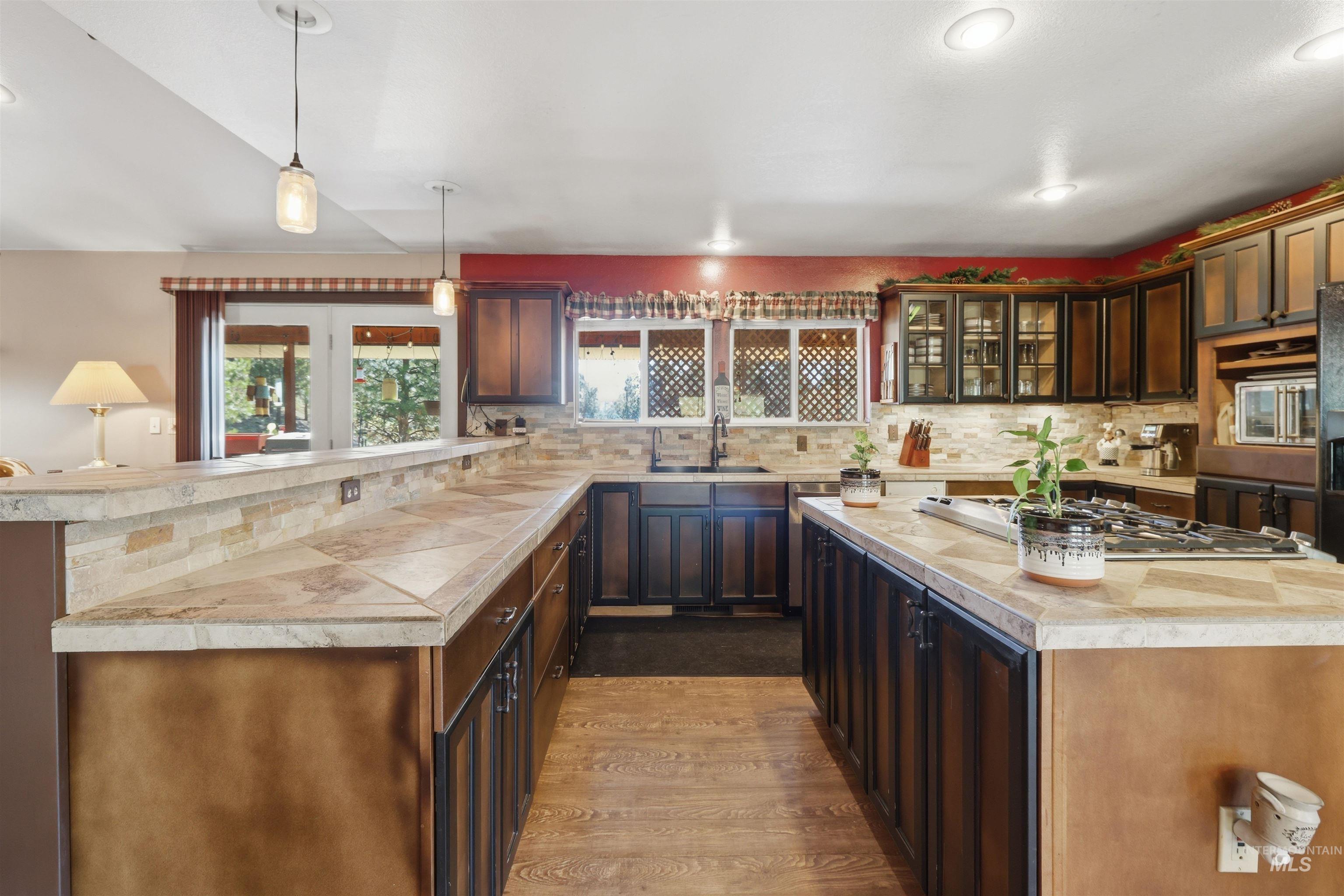 95 Johnson Creek Road Boise, ID 83716 - Photo 20 of 49 Kitchen with a peninsula, light countertops, dark wood-style floors, glass insert cabinets, and stainless steel appliances