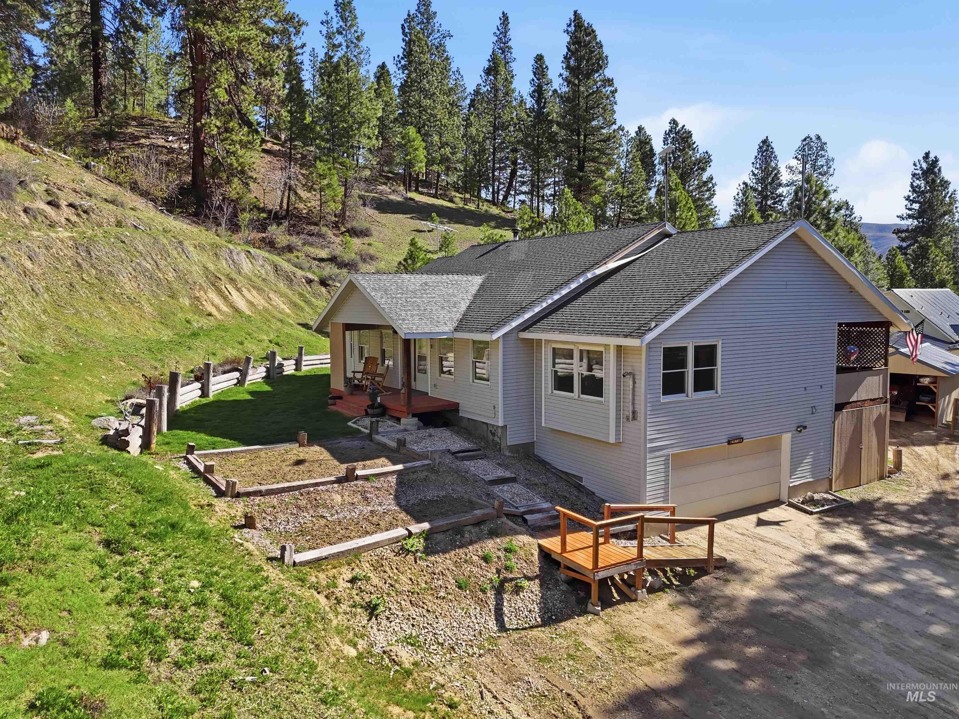 95 Johnson Creek Road Boise, ID 83716 - Photo 2 of 49 Back of house with a garage, roof with shingles, driveway, view of scattered trees, and a porch