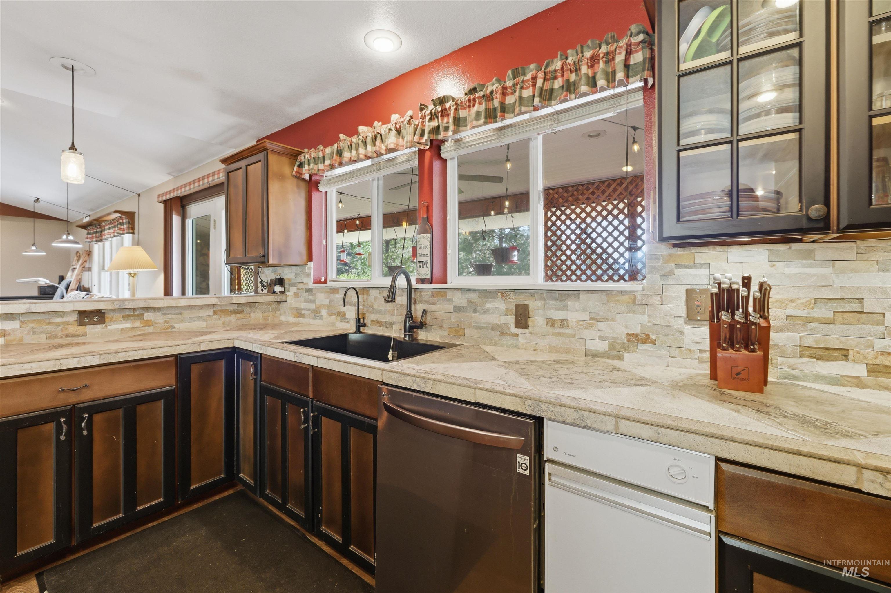 95 Johnson Creek Road Boise, ID 83716 - Photo 23 of 49 Kitchen with dishwasher, hanging light fixtures, a peninsula, tasteful backsplash, and glass fronted cabinets