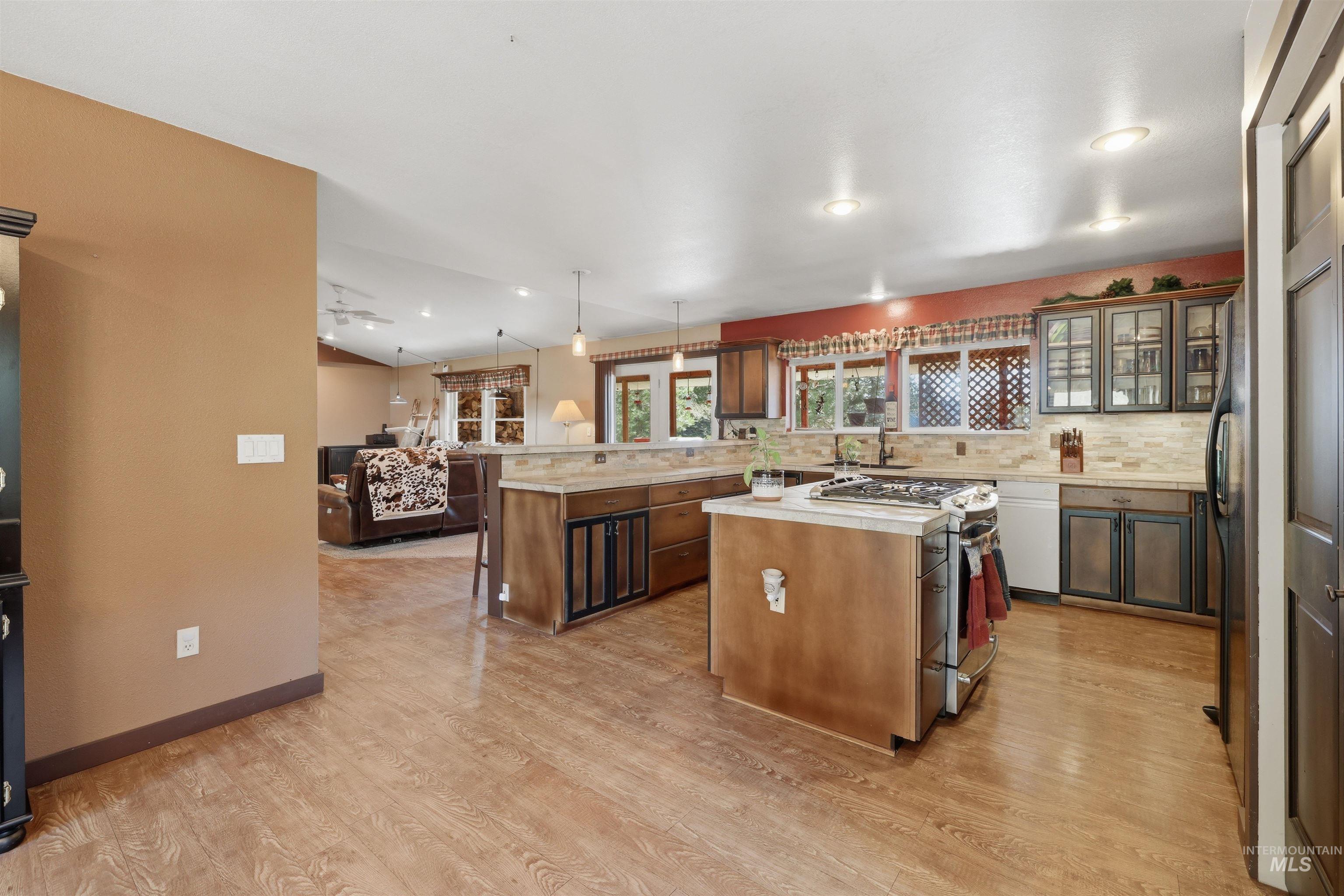 95 Johnson Creek Road Boise, ID 83716 - Photo 24 of 49 Kitchen with stainless steel gas range, decorative light fixtures, glass fronted cabinets, tasteful backsplash, and light wood-style floors