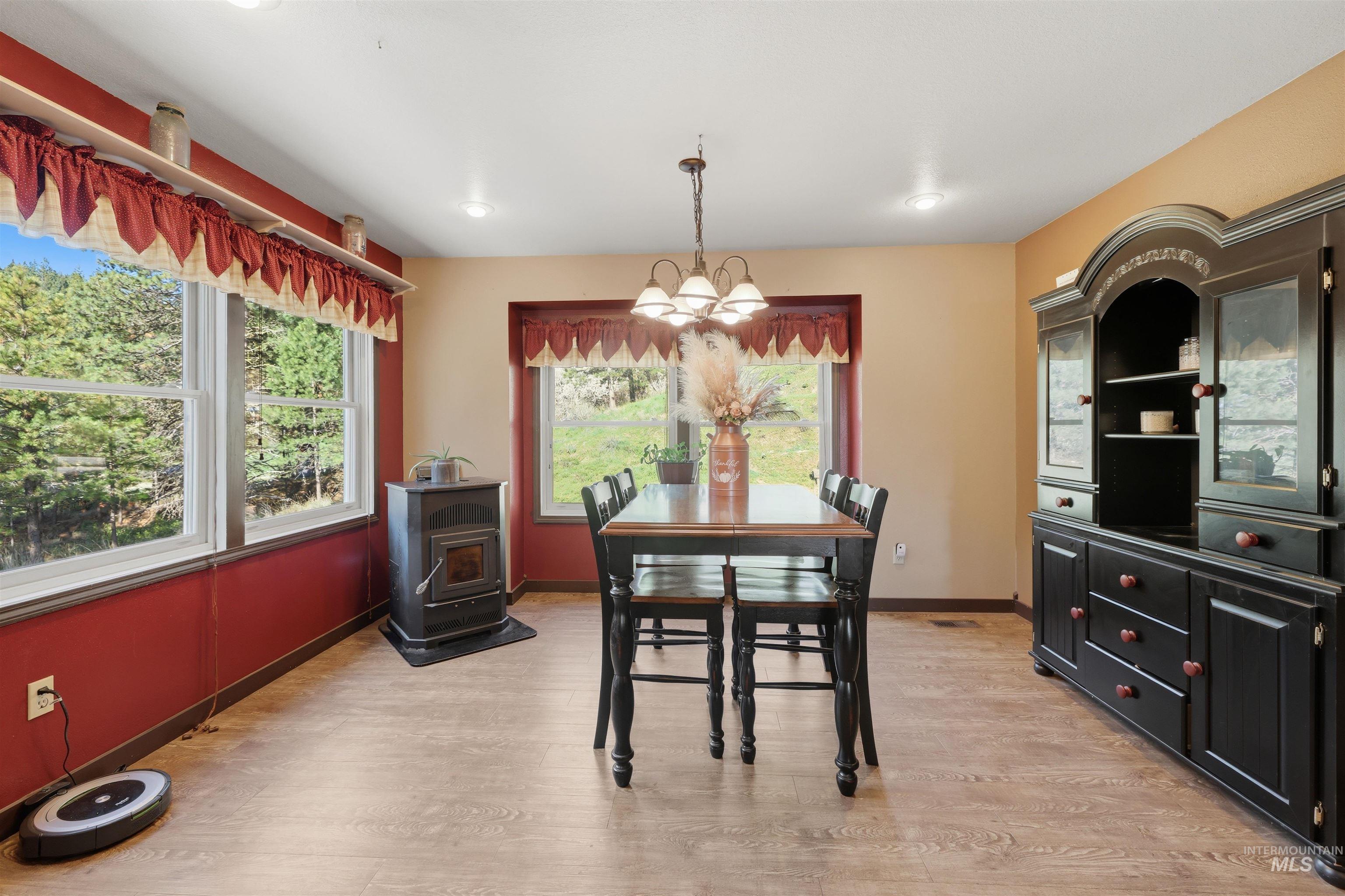 95 Johnson Creek Road Boise, ID 83716 - Photo 25 of 49 Dining space featuring a wood stove, light wood-type flooring, and hanging lights