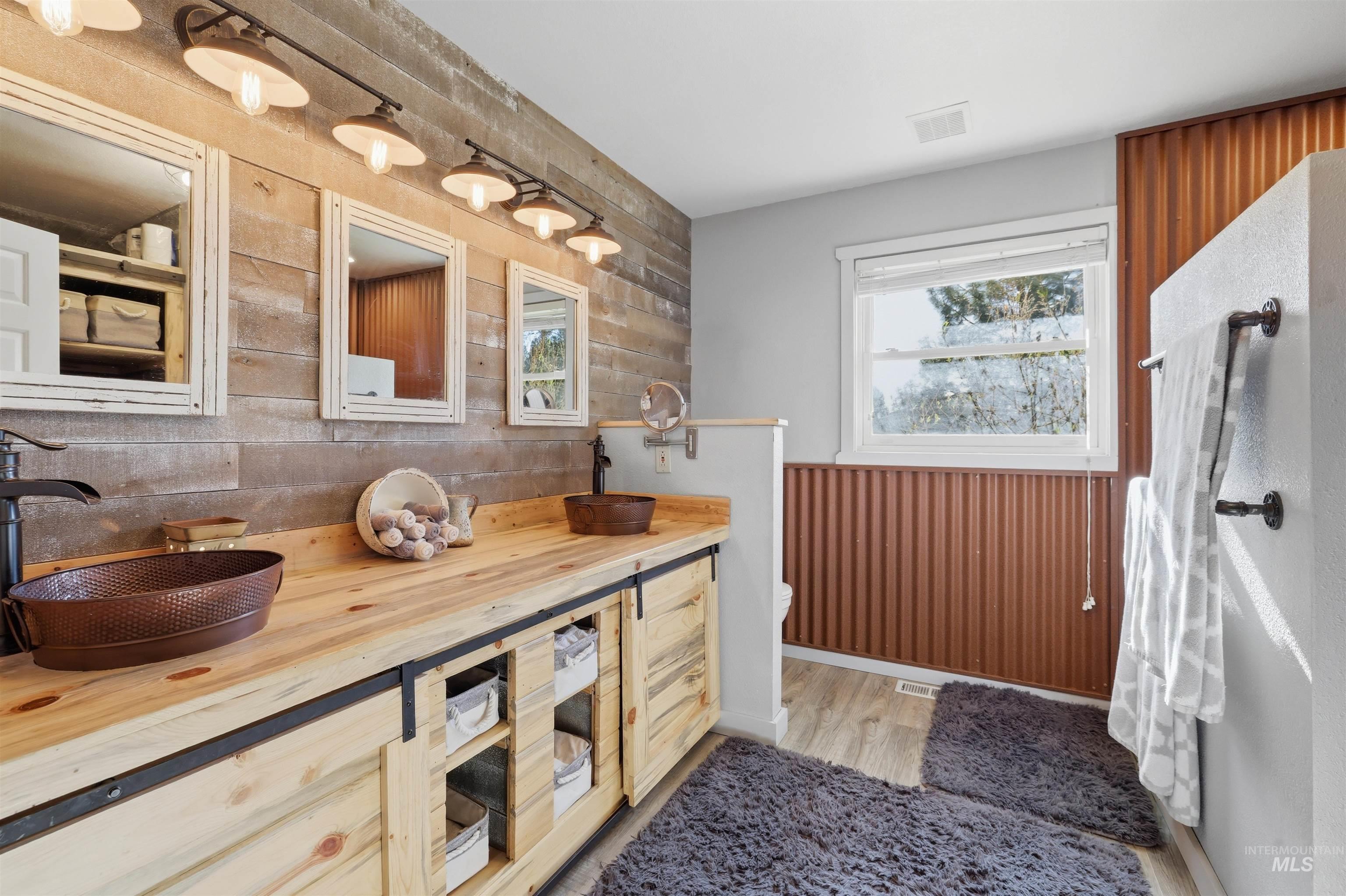 95 Johnson Creek Road Boise, ID 83716 - Photo 29 of 49 Bathroom with double vanity, wooden walls, and light wood-type flooring
