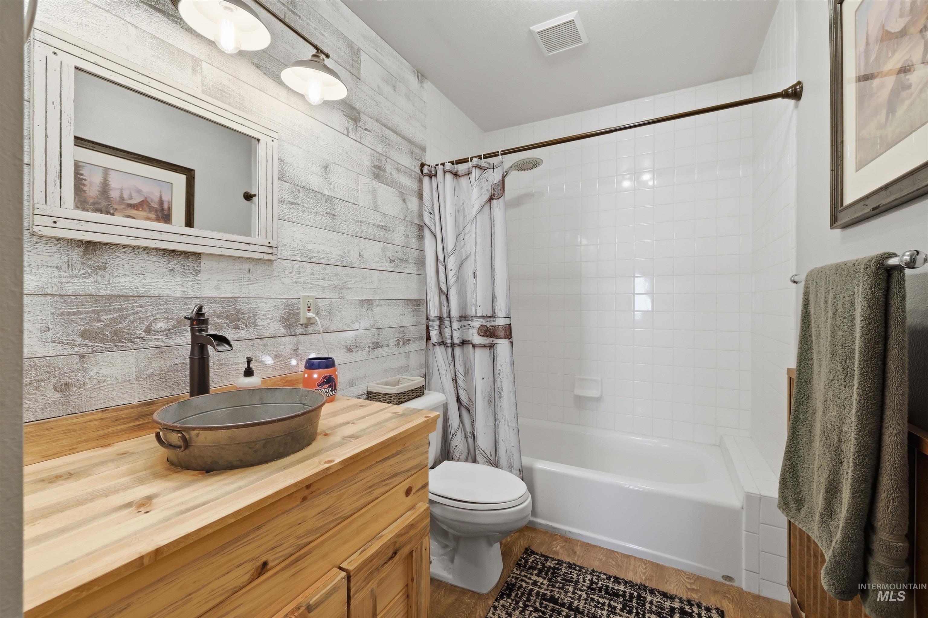 95 Johnson Creek Road Boise, ID 83716 - Photo 33 of 49 Bathroom featuring vanity, shower / bath combo, wood finished floors, and wooden walls