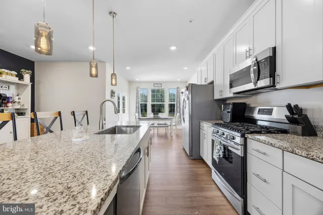 a large kitchen with stainless steel appliances granite countertop a lot of counter space a sink and a wooden floors
