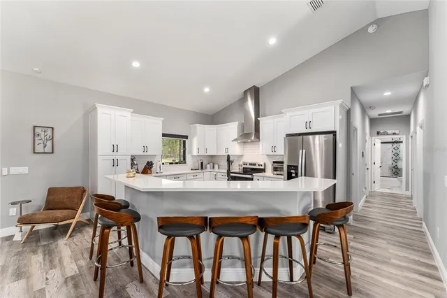 a kitchen with stainless steel appliances a dining table chairs refrigerator and sink
