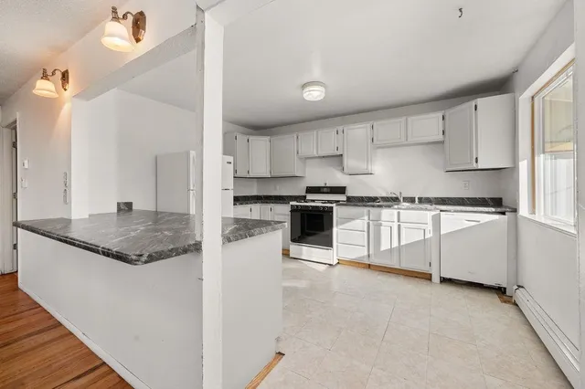 a kitchen with granite countertop white cabinets and white appliances