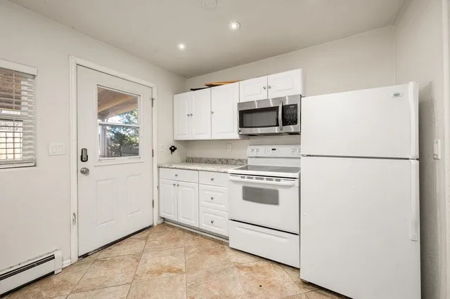 a kitchen with granite countertop white cabinets and refrigerator