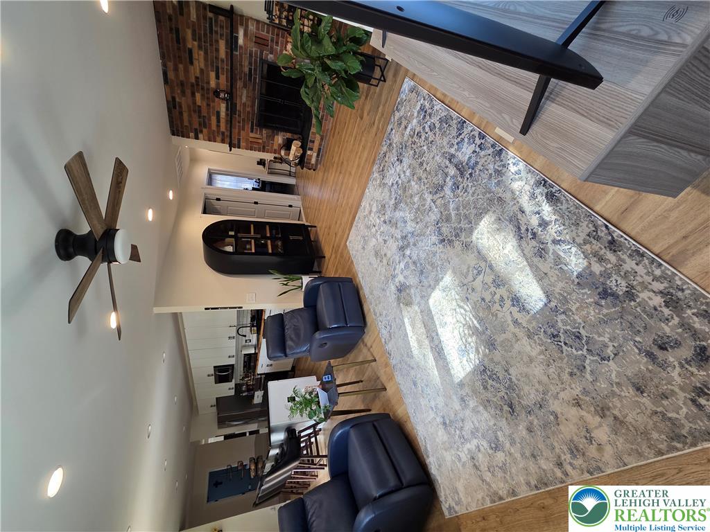 Warm hardwood flooring runs underfoot throughout this inviting living space anchored by a brick fireplace.