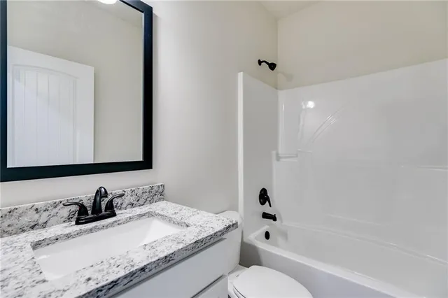 a bathroom with a granite countertop sink mirror toilet and bathtub