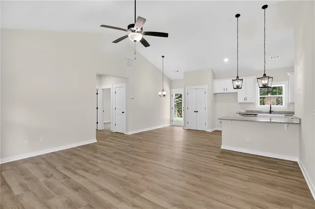 a view of a kitchen with kitchen island a sink wooden floor and a ceiling fan