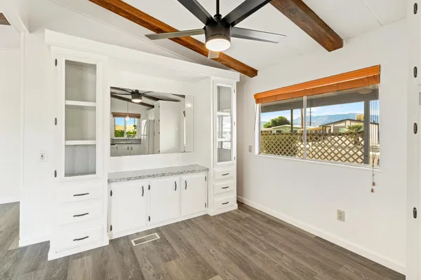 a view of a kitchen with wooden floor and white cabinets
