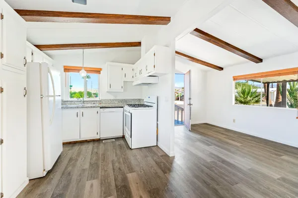 a kitchen with a hard wood floor white cabinets and white appliances