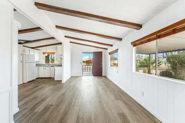 a view of a big room with wooden floor and windows