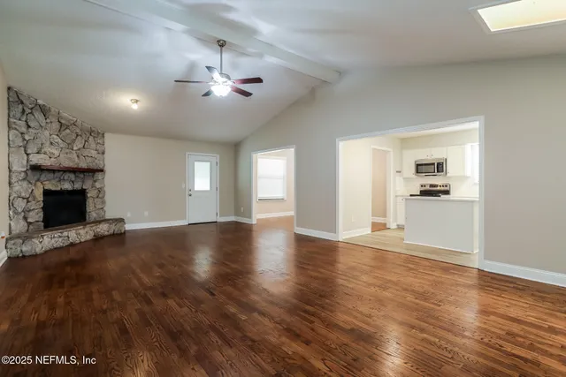 a view of an empty room with window and wooden floor