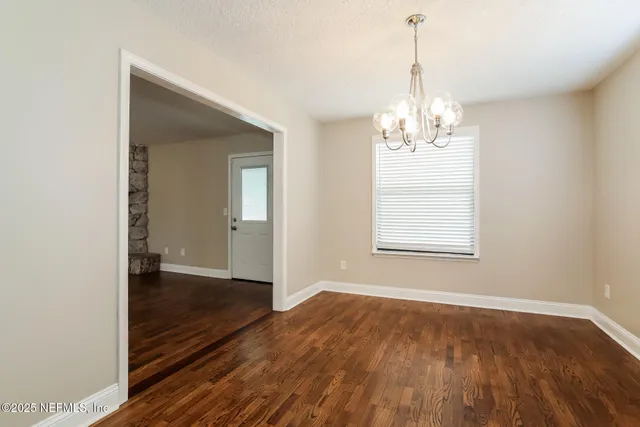 a view of a room with wooden floor chandelier and a window