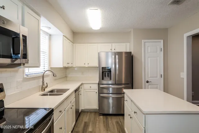 a kitchen with a sink a refrigerator and a stove top oven with wooden floor